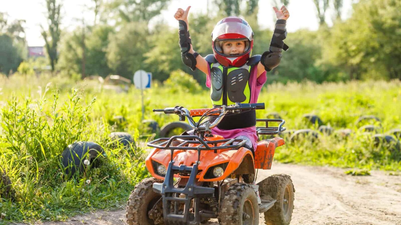 child on dirt track riding an electric quad bike