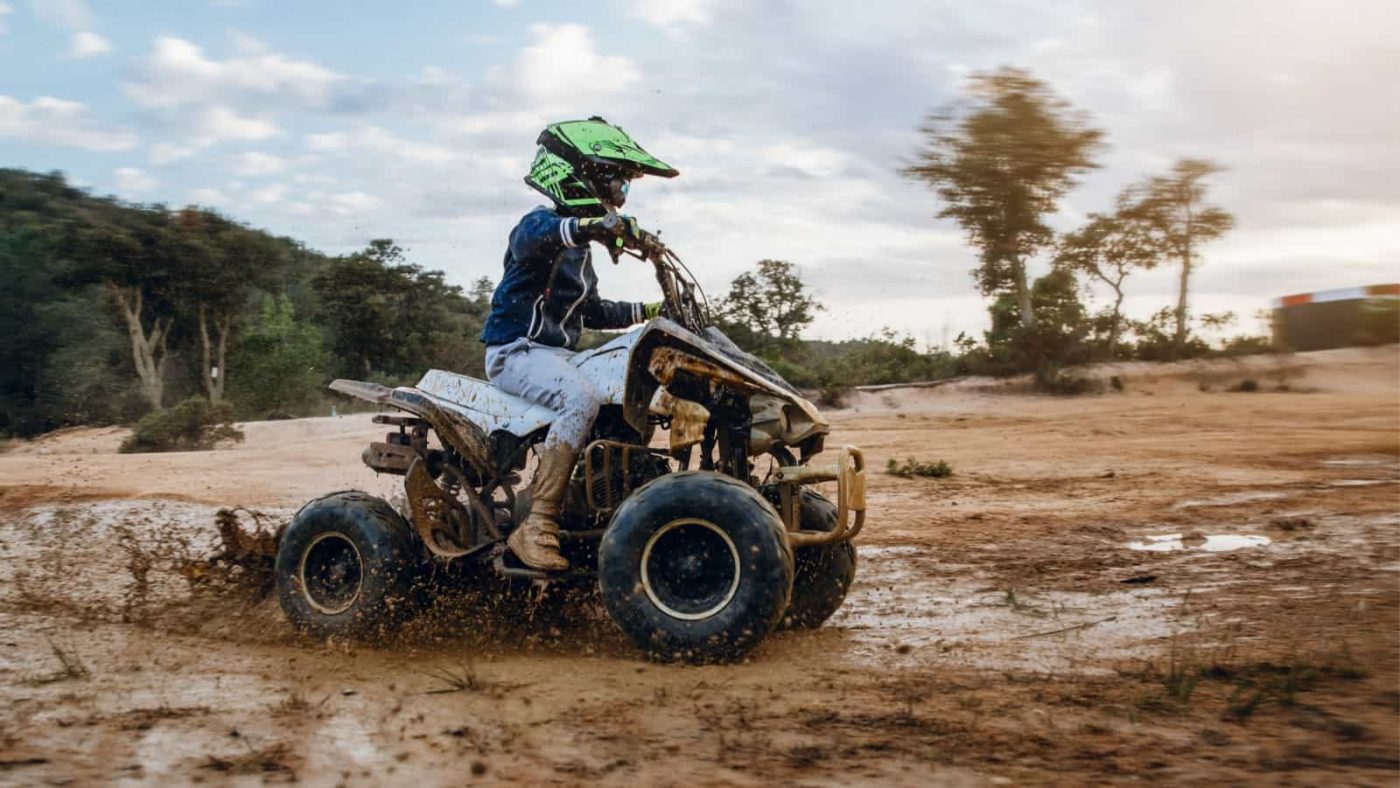 electric quad bike being driven by child in mud