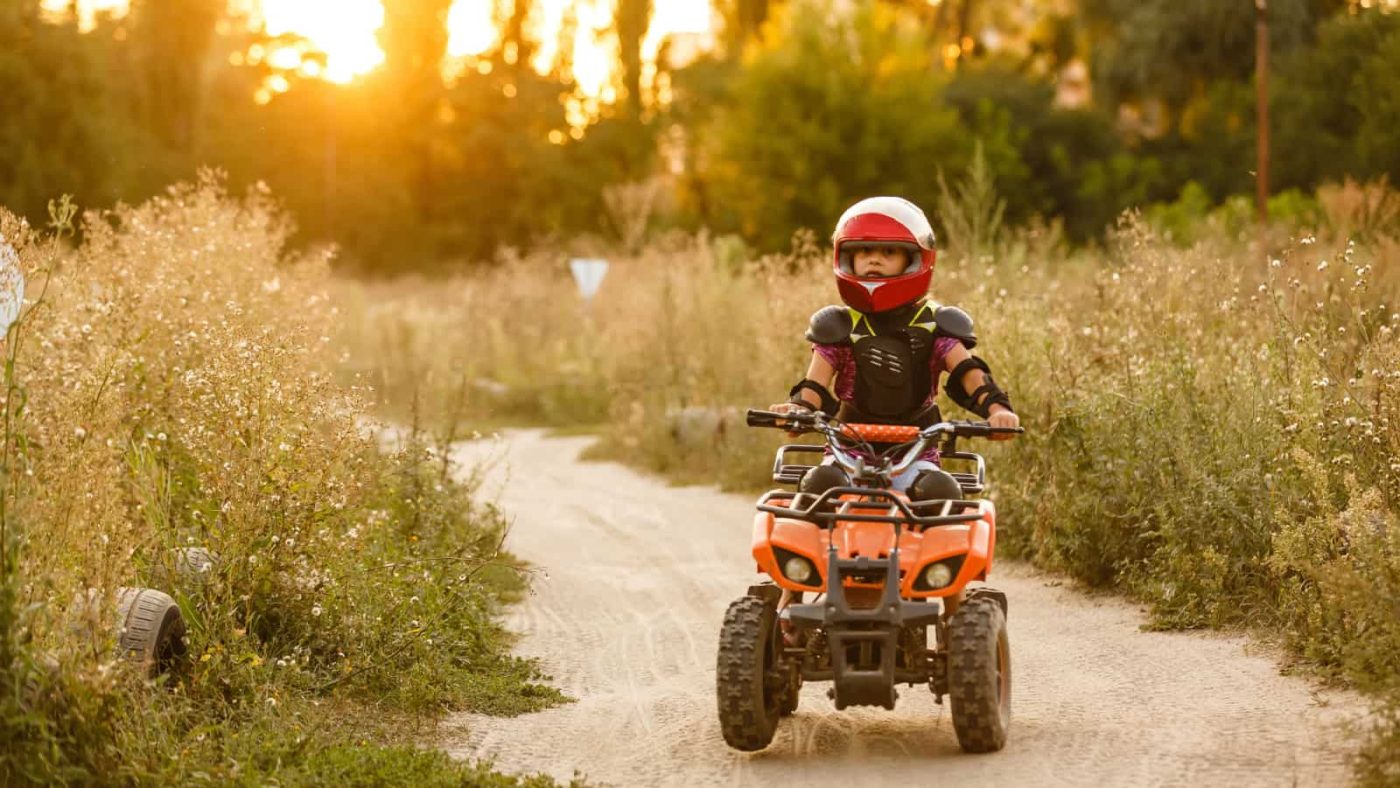 kid riding on path on red electric quad bike